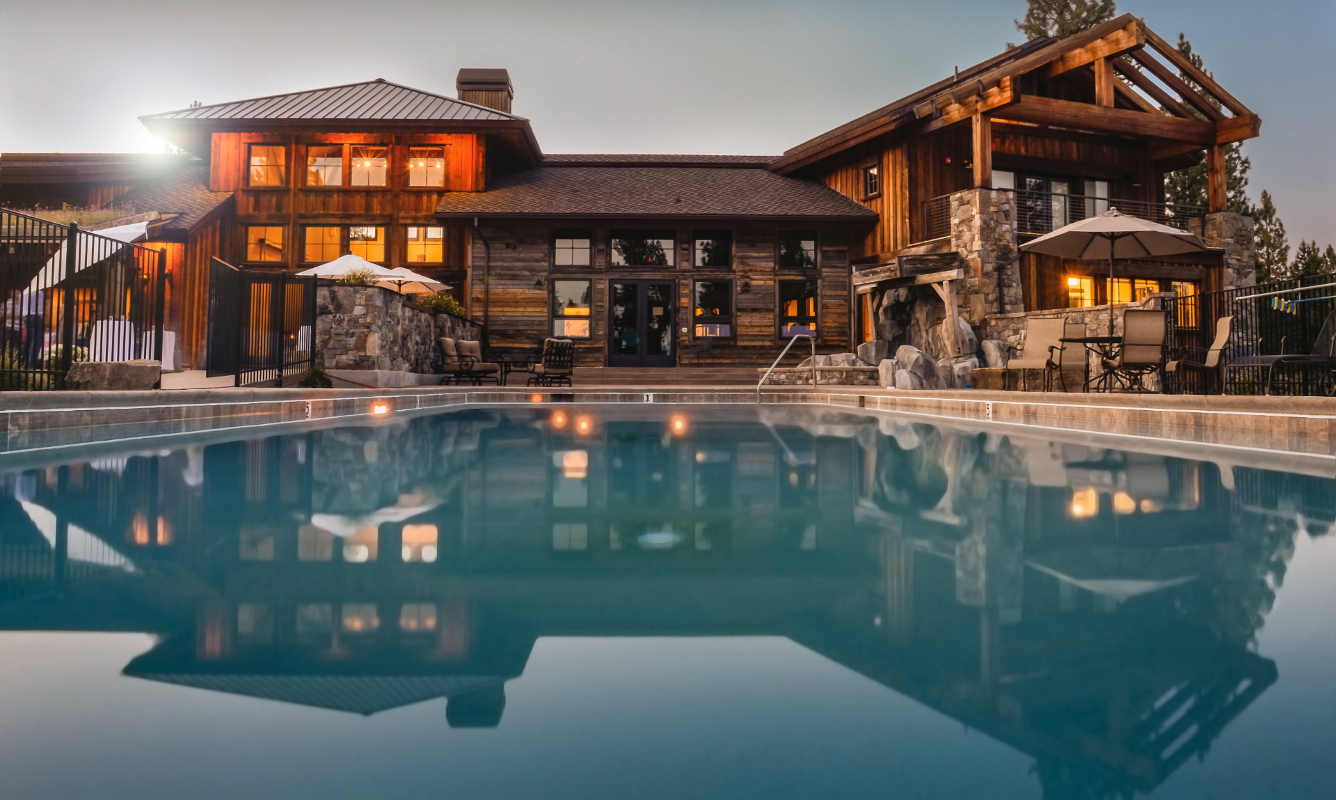 Rustic luxury mountain lodge with pool at dusk