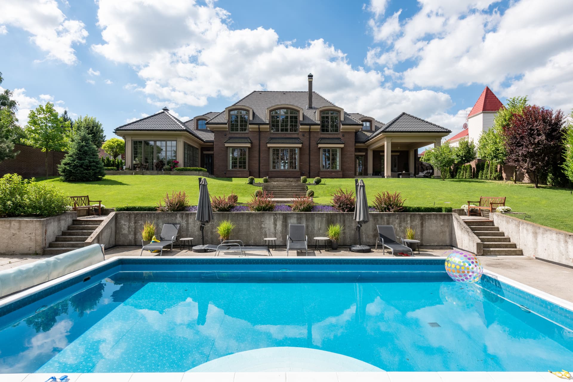 Brick estate home with terraced lawn and swimming pool