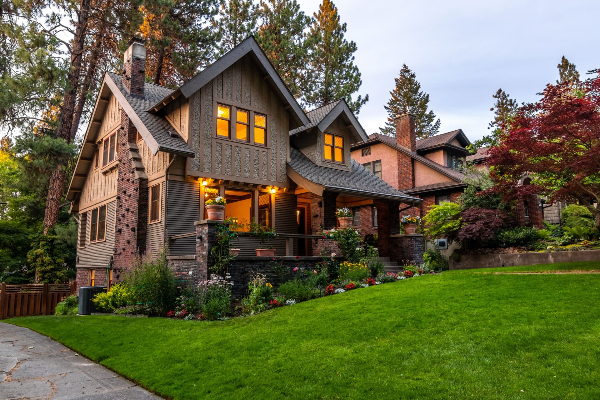 Craftsman home with warm lit windows and manicured lawn